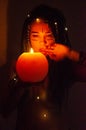 Girl with blue dreadlocks conjures at night in a dark room, candle fire and a cow skull.