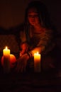 Girl with blue dreadlocks conjures at night in a dark room, candle fire and a cow skull  . Royalty Free Stock Photo