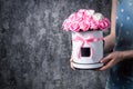 A girl in a blue dress is holding a bouquet of red and white, pink and white roses in a hat box. Dark gray background. Royalty Free Stock Photo