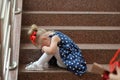 Little girl in a blue dress sits on the steps and cries Royalty Free Stock Photo