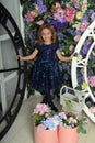 Girl in a blue dress with sparkles, happy child with a smile on a background of a wall with flowers and two clock faces Royalty Free Stock Photo