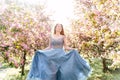 A girl in a blue flowing dress walks through a pink blooming garden. Royalty Free Stock Photo
