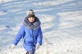 A girl in a blue jacket is climbing a snowy hill