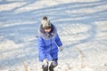 A girl in a blue jacket is climbing a snowy hill