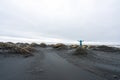 Girl with blue jacket are standing on a sand dune with arms raised in Stokksnes and celebrates the view.