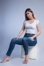 Elegant and Chic: Vertical Studio Portrait of a Young Woman in Blue Jeans and Bare Feet Royalty Free Stock Photo