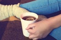 A girl in blue jeans holds a cup of tea and lemon in her hand. Close-up, soft focus Royalty Free Stock Photo