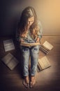 Girl in blue jeans and a plaid shirt with long wavy hair sitting floor reading a book retro toning