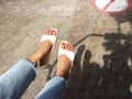 Girl in Blue Jeans and White Shoes from Top View. Woman Wearing White Sandals of Accessory on Concrete Background Royalty Free Stock Photo