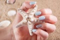 Summer Serenity: Young Female Hand Holding a Starfish on Sandy Beach