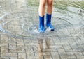 Girl in blue rubber boots standing in a puddle after a rain Royalty Free Stock Photo