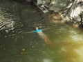 A girl in a blue swimsuit swims on her back in the muddy water of a rocky gorge in sun glare Royalty Free Stock Photo