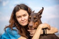 Girl in a blue T-shirt hugs a Doberman Dobermann dog. Portrait against the sky. Horizontal orientation. Royalty Free Stock Photo