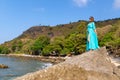 girl in a blue tunic on a stone sea beach Royalty Free Stock Photo