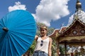 Girl with a blue umbrella in her hands playing with it in front of a Buddhist temple Royalty Free Stock Photo