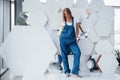 Girl in blue uniform stands against abstract wall with white pieces of surface in the shape of hexagon in the auto