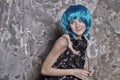 Girl in blue wig smiling with headphones on cement wall Royalty Free Stock Photo