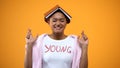 Girl with book on her head crossing fingers, students rituals for better memory