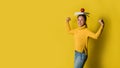 A girl with a book on her head and a red apple in her hand while doing yoga on yellow background. The concept of exercise for good