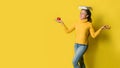 A girl with a book on her head and a red apple in her hand while doing yoga on yellow background. The concept of exercise for good