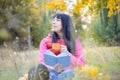 A girl with a book is sitting in the autumn park. A woman drinks coffee and reads literature in the forest. A lady with a cup in