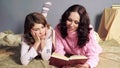 Girl bored with storybook her mother reading before bedtime, togetherness