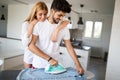 Girl bothering boyfriend while ironing shirt