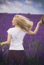 A girl with a bouquet of flowers in a lilac lushly field.