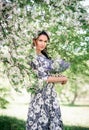 Girl with a bouquet of lilacs. A beautiful woman in a summer dress under a cherry blossom. A young girl against the background of