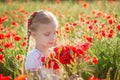 Girl with bouquet among poppies field at sinset