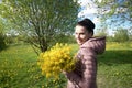 Girl with a bouquet of yellow rape. In the spring meadow. The sun shines brightly