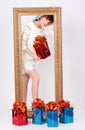Girl with box with gift stands behind gilt frame Royalty Free Stock Photo
