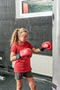 A girl in boxing gloves hits a punching bag in the gym