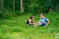 Girl and a boy in boots are sitting and putting mushrooms they found in the forest into a basket Royalty Free Stock Photo