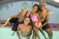 Girl (5-6) boy (7-9) boy (10-12) with grandfather at pool elevated view portrait.