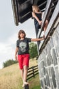 Girl and boy climbing over a wooden fence around house Royalty Free Stock Photo