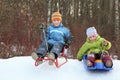 Girl and boy go downward from hill on sledges Royalty Free Stock Photo