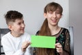 Girl and boy holding sheet of green paper for your text Royalty Free Stock Photo