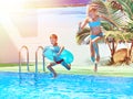 Girl and boy jumping into resort pool Royalty Free Stock Photo