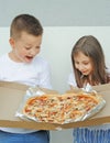 A girl and a boy are looking at big delicious pizza in a box Royalty Free Stock Photo