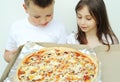 A girl and a boy are looking at big delicious pizza in a box Royalty Free Stock Photo