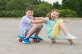 Girl and boy in the Park outdoors, riding sitting on sports boards, building funny grimaces