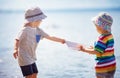 Girl and boy playing on the beach in summer hats and holding paper ships Royalty Free Stock Photo