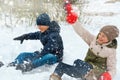 A girl and a boy are playing snowballs outside, beautiful winter weather and white snow around Royalty Free Stock Photo