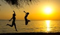 Girl and boy silhouettes jumping on the beach at sunset Royalty Free Stock Photo