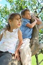 Girl and boy sit on caudex of lilac and look aside Royalty Free Stock Photo