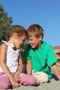 Girl and boy sit on sand