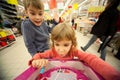 Girl and boy sit in shoppingcart, play new toy Royalty Free Stock Photo