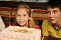 A girl and a boy are sitting in a cafe near a big cake. They have a good mood and appetite Royalty Free Stock Photo