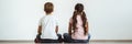 The girl and a boy sitting on the floor on the white wall background. Royalty Free Stock Photo